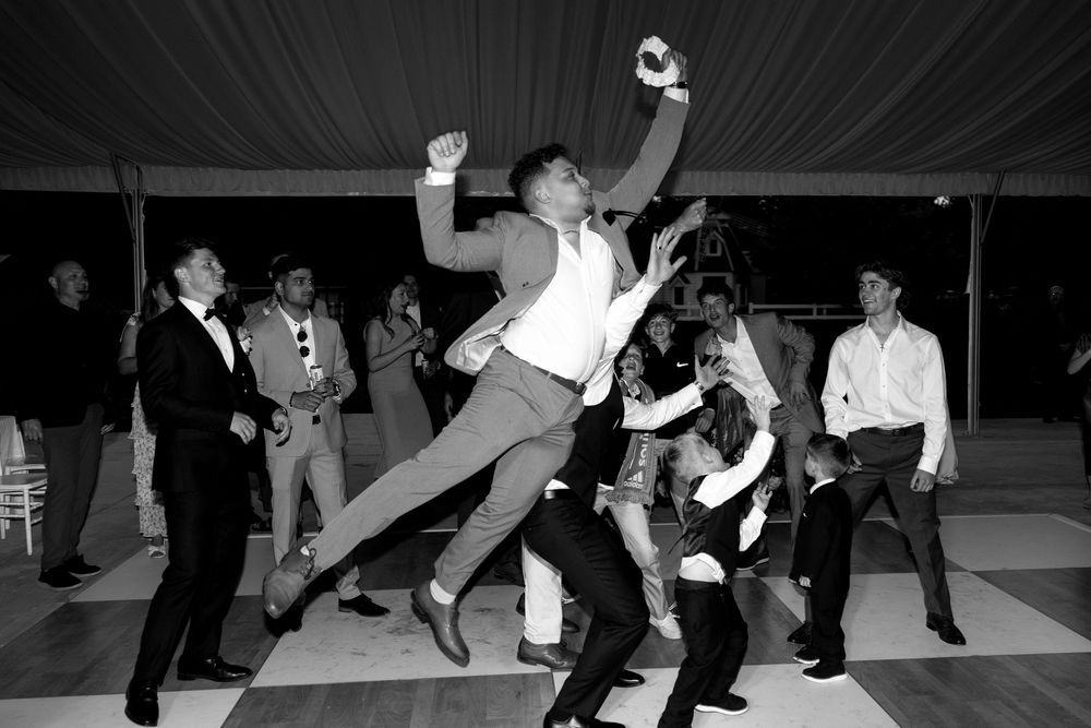 A group of dancers perform energetic swing dance moves on a dance floor in black and white photography.