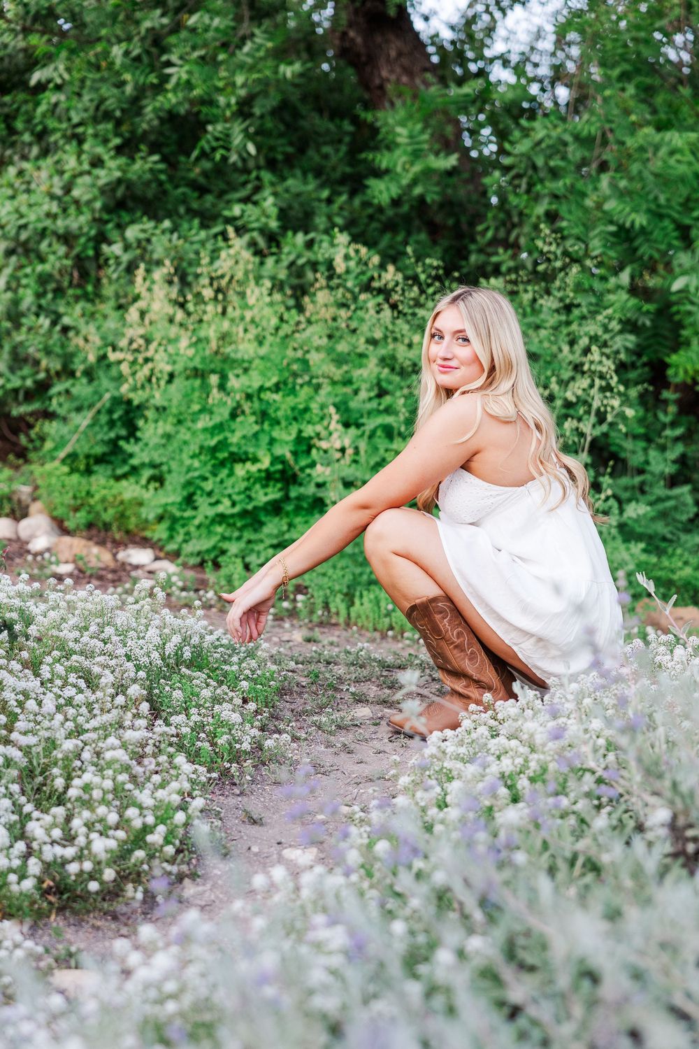 Artistic portrait session among delicate white wildflowers and lush greenery in a natural garden setting.