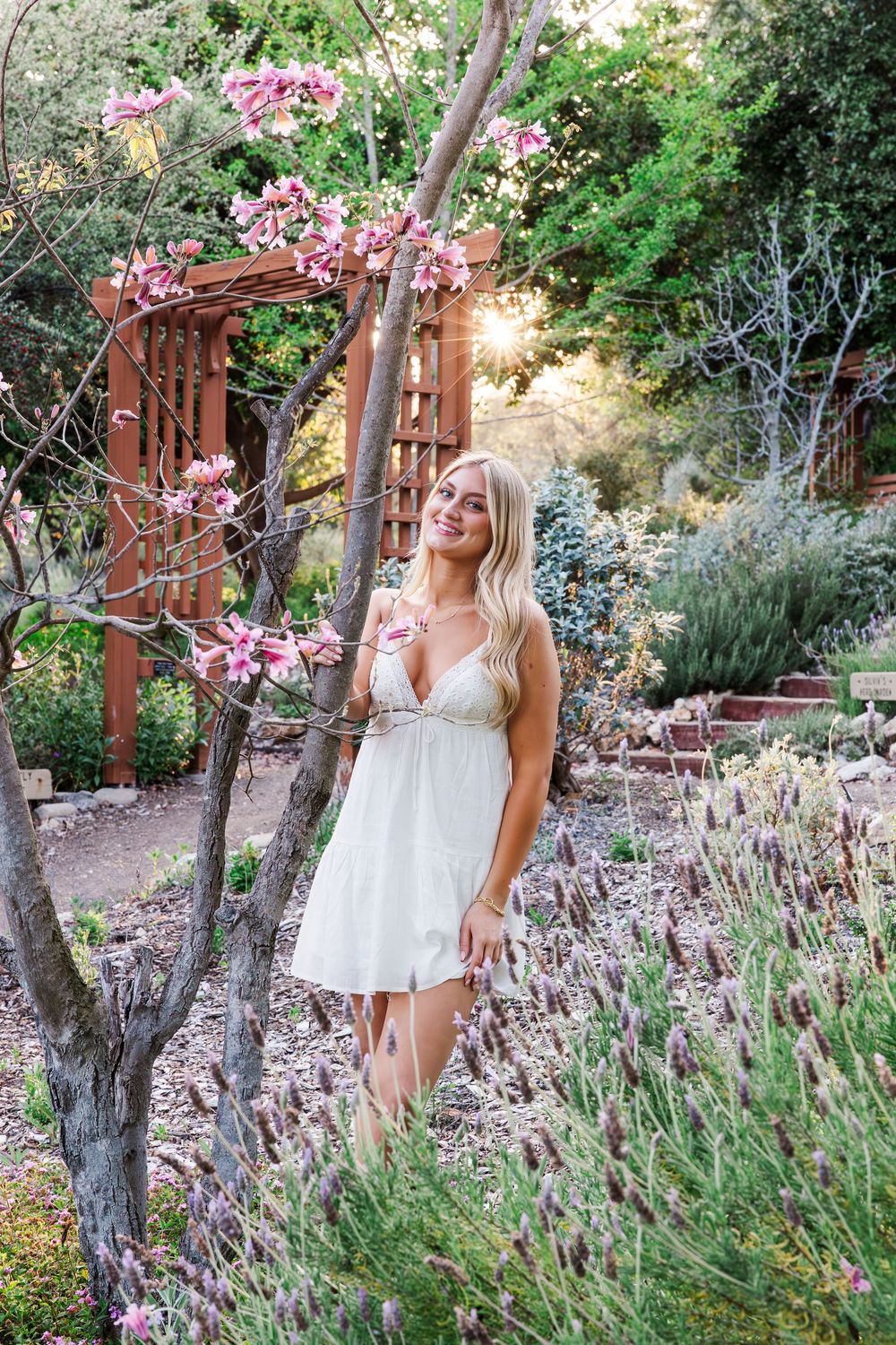 White lace dress contrasts beautifully against a garden backdrop with blooming lavender and pink flowers on a sunny day.
