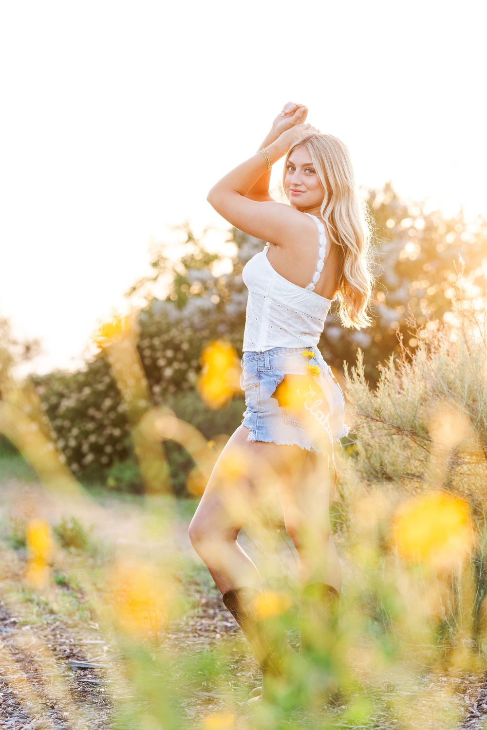 Summer portrait in a field with golden sunlight and yellow wildflowers.