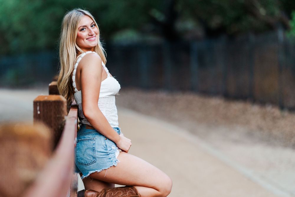 Casual outdoor portrait combining denim shorts and a white top in a garden setting.