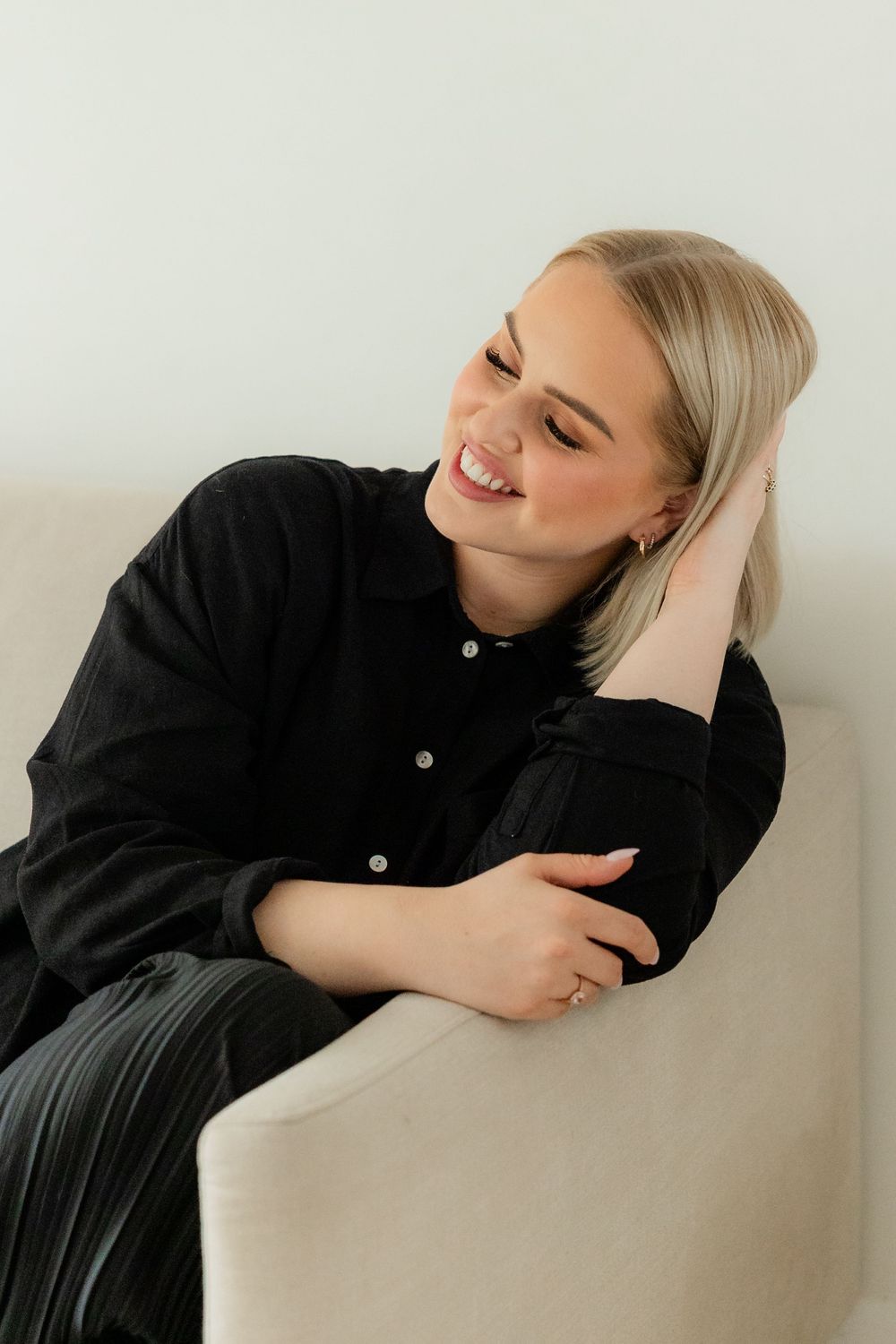 Person in black clothing leaning against white wall in artistic photo sequence showing progressive movement.