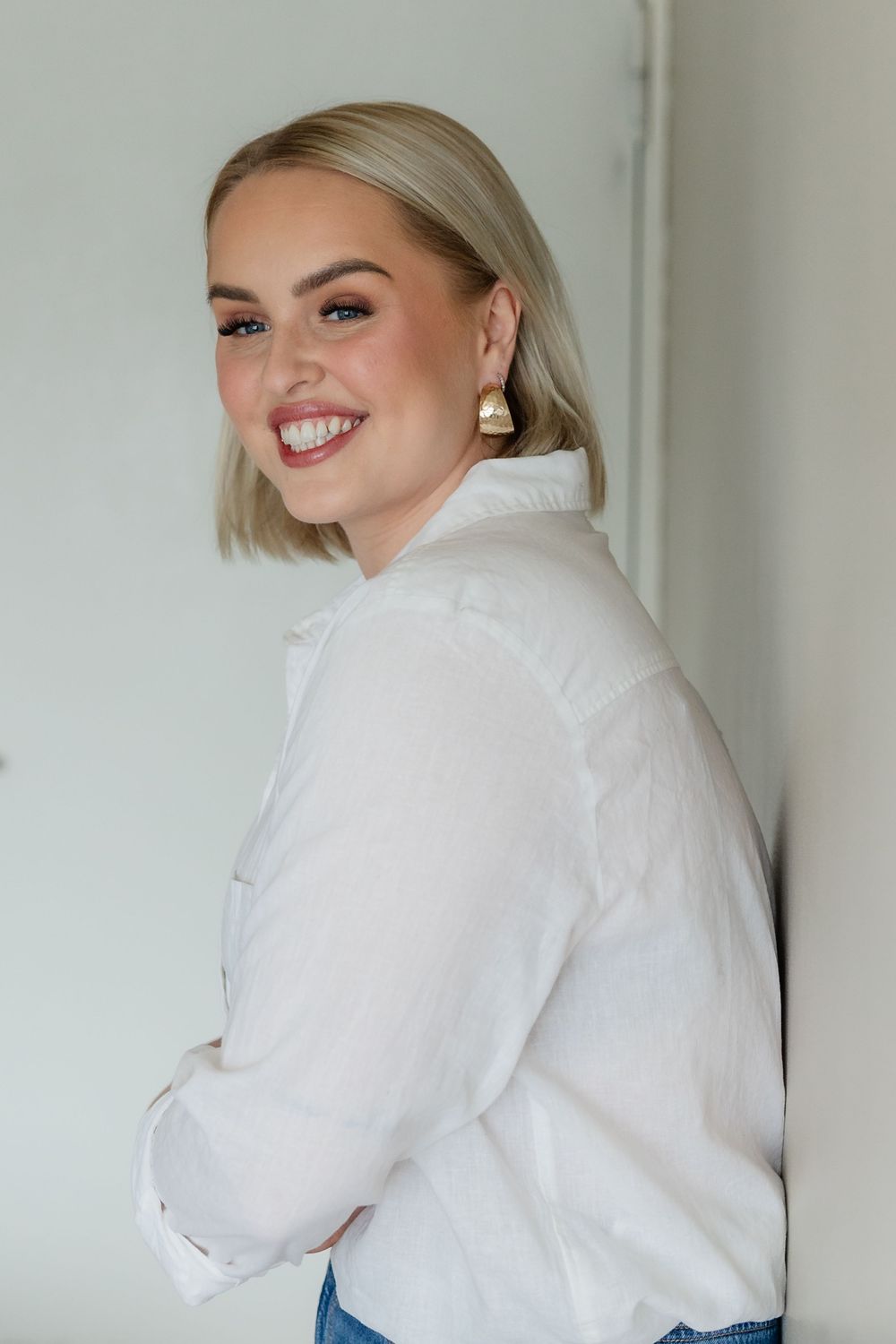 A person in a white button-down shirt smiles and poses in a series of casual shots against a light background.