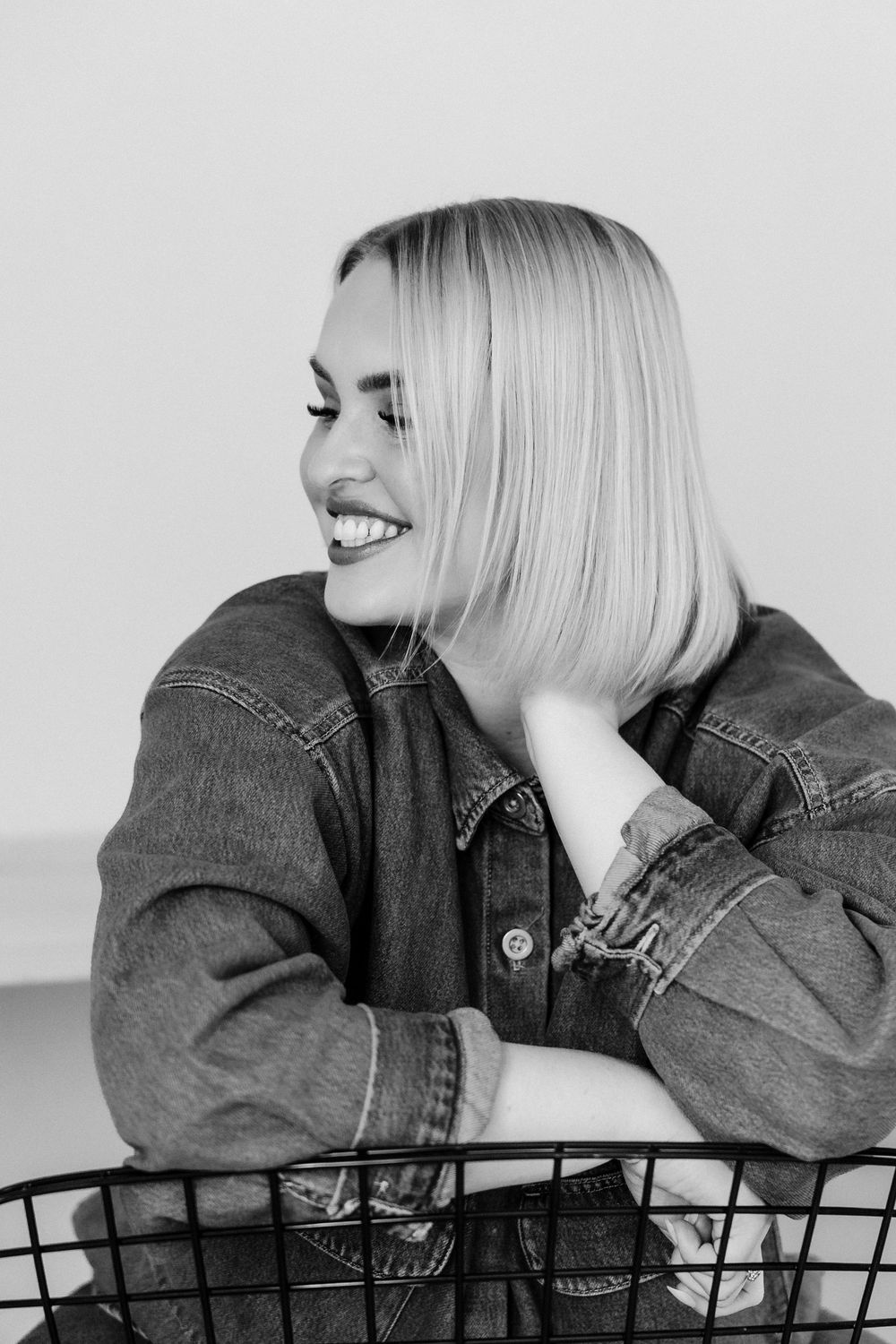 Black and white photo series of someone in denim posing with cheerful expressions against a plain backdrop.