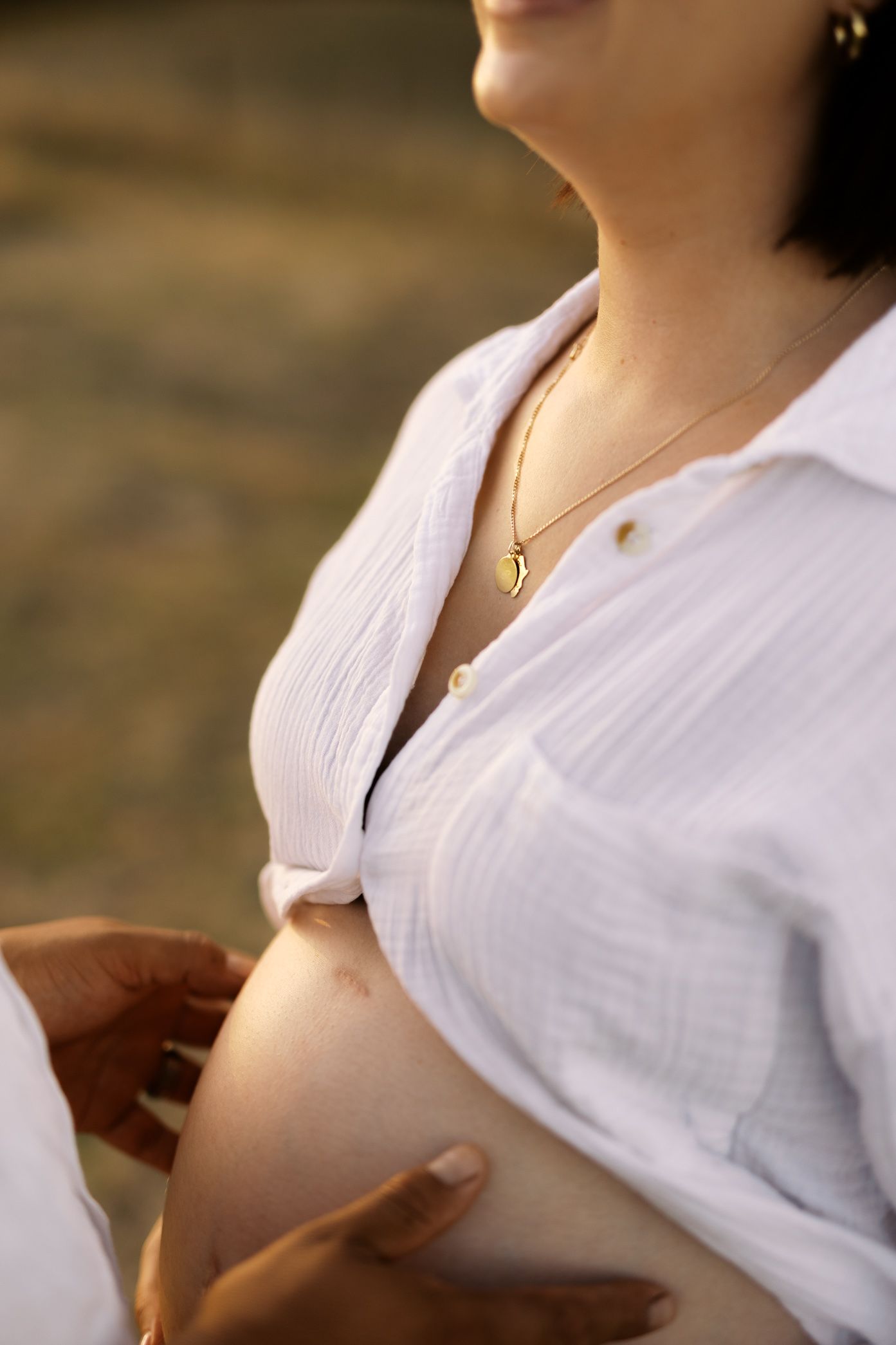 A person wearing a white collared shirt stands in warm lighting creating a soft, glowing profile silhouette.