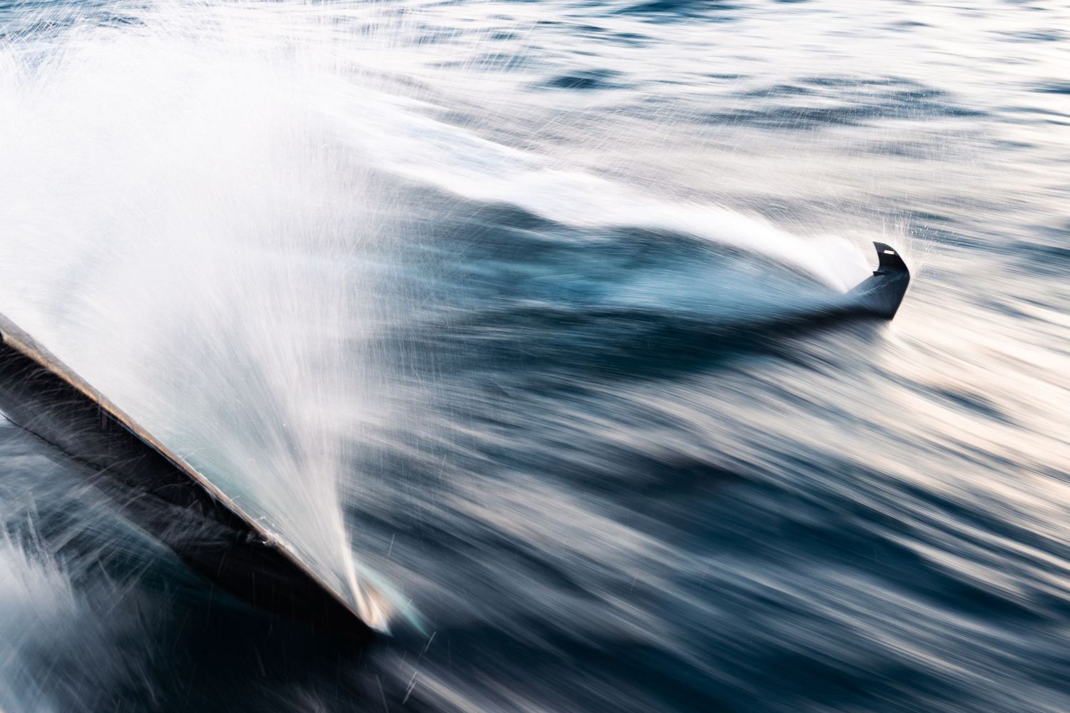 Abstract view of ocean waves creating white foam patterns against dark water.