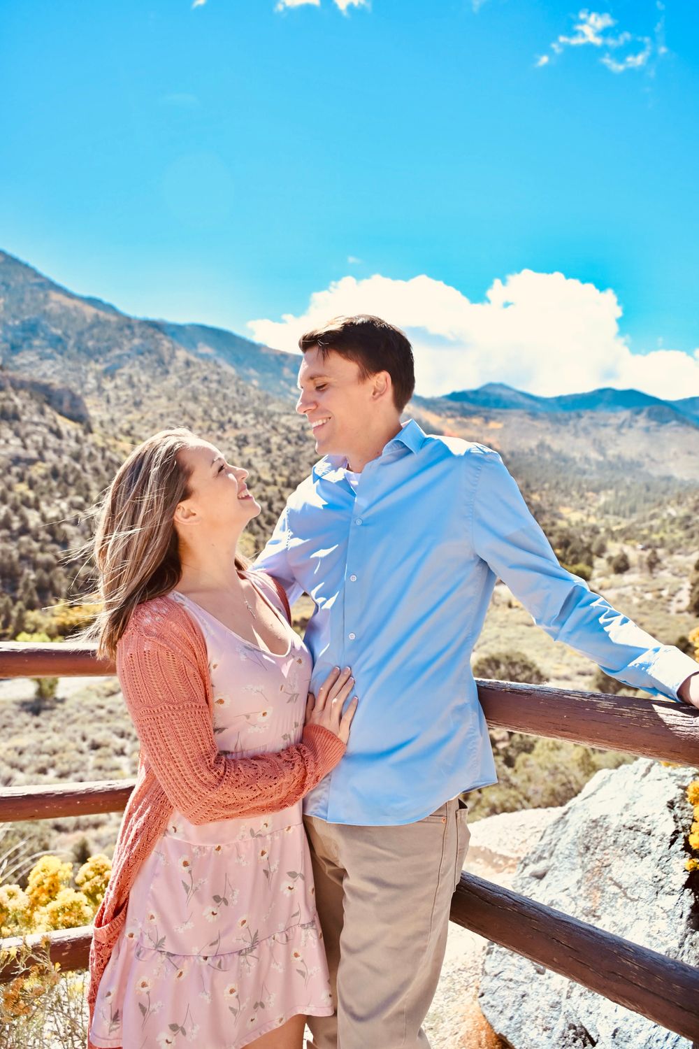 Happy couple embracing and smiling at each other on a scenic mountain overlook on a sunny day.