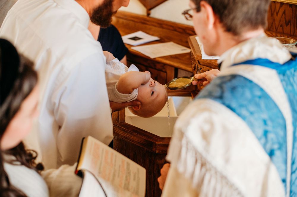 Water is poured over the head of a newborn boy as he is Baptized into the Catholic Church.
