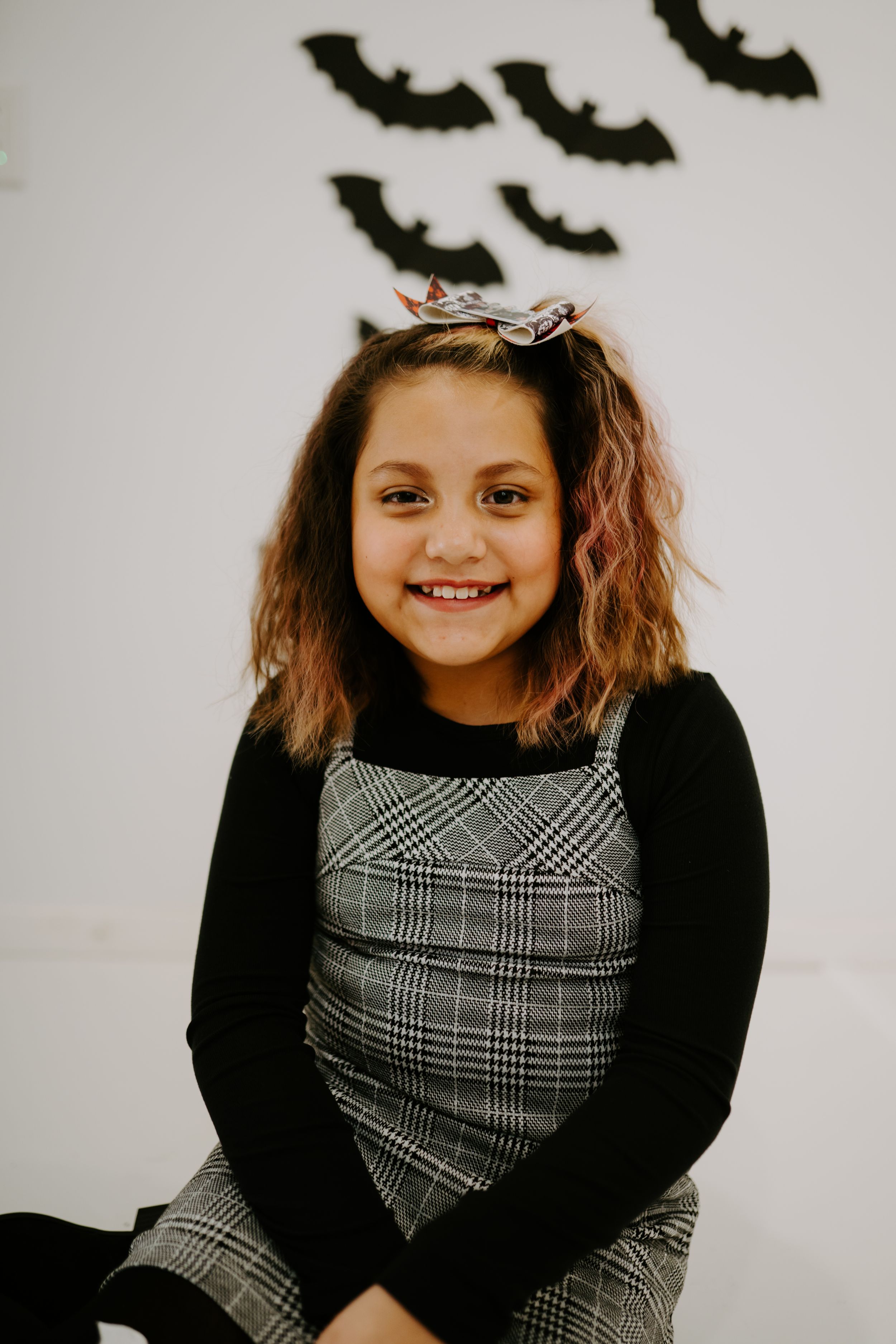 A festive Halloween photo with plaid dress and black decor against a white backdrop.