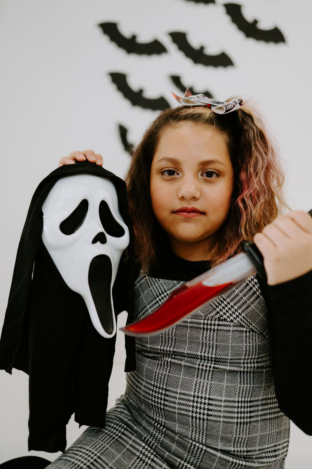 A spooky Halloween scene with a classic ghost mask and plaid dress.