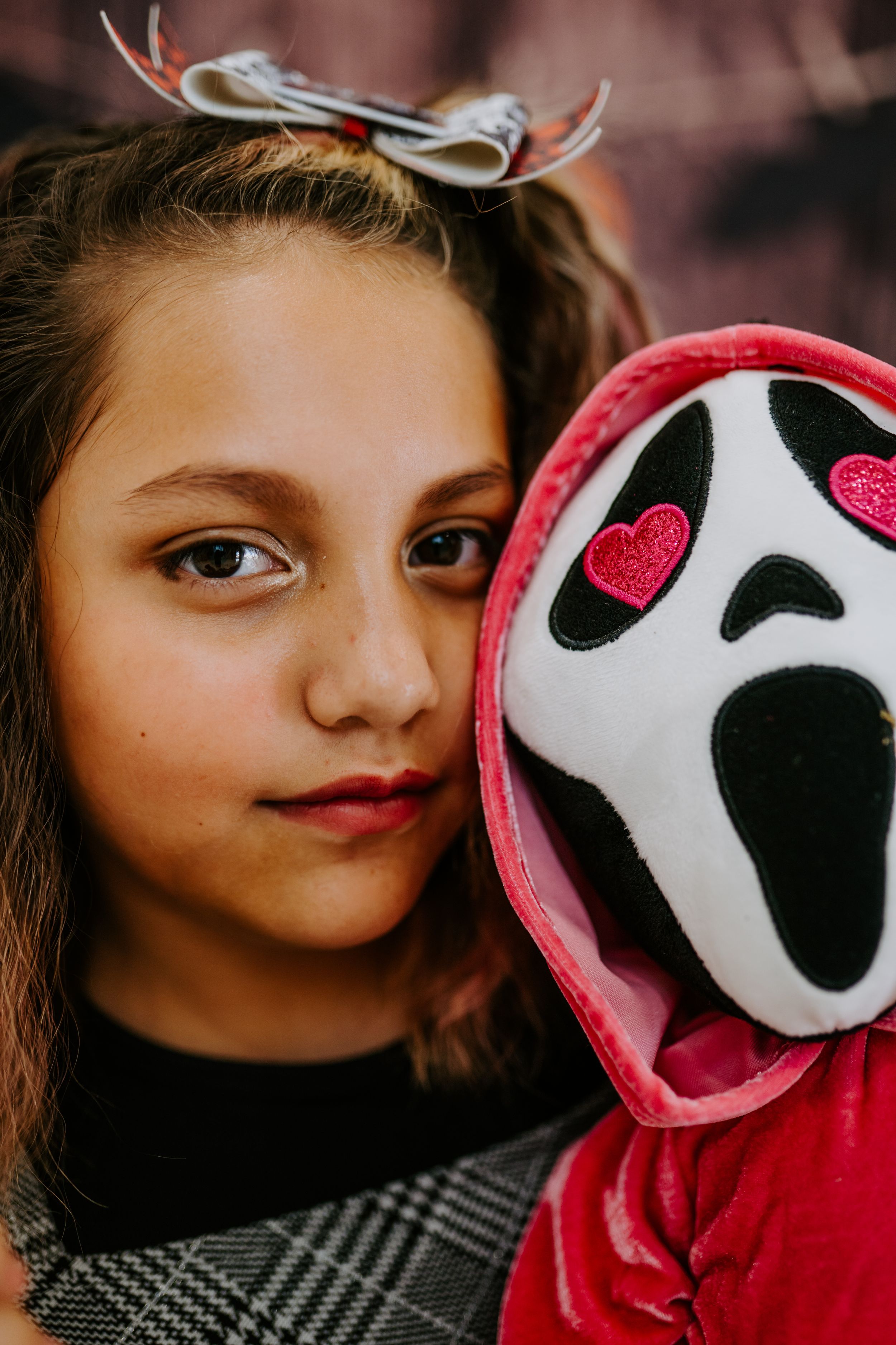 A close-up Halloween portrait with a red and white ghost mask prop.