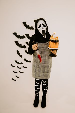 A Halloween costume featuring ghost patterns and plaid dress with bat decorations.