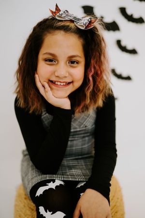 Portrait against white wall with flying bat decorations in Halloween theme.
