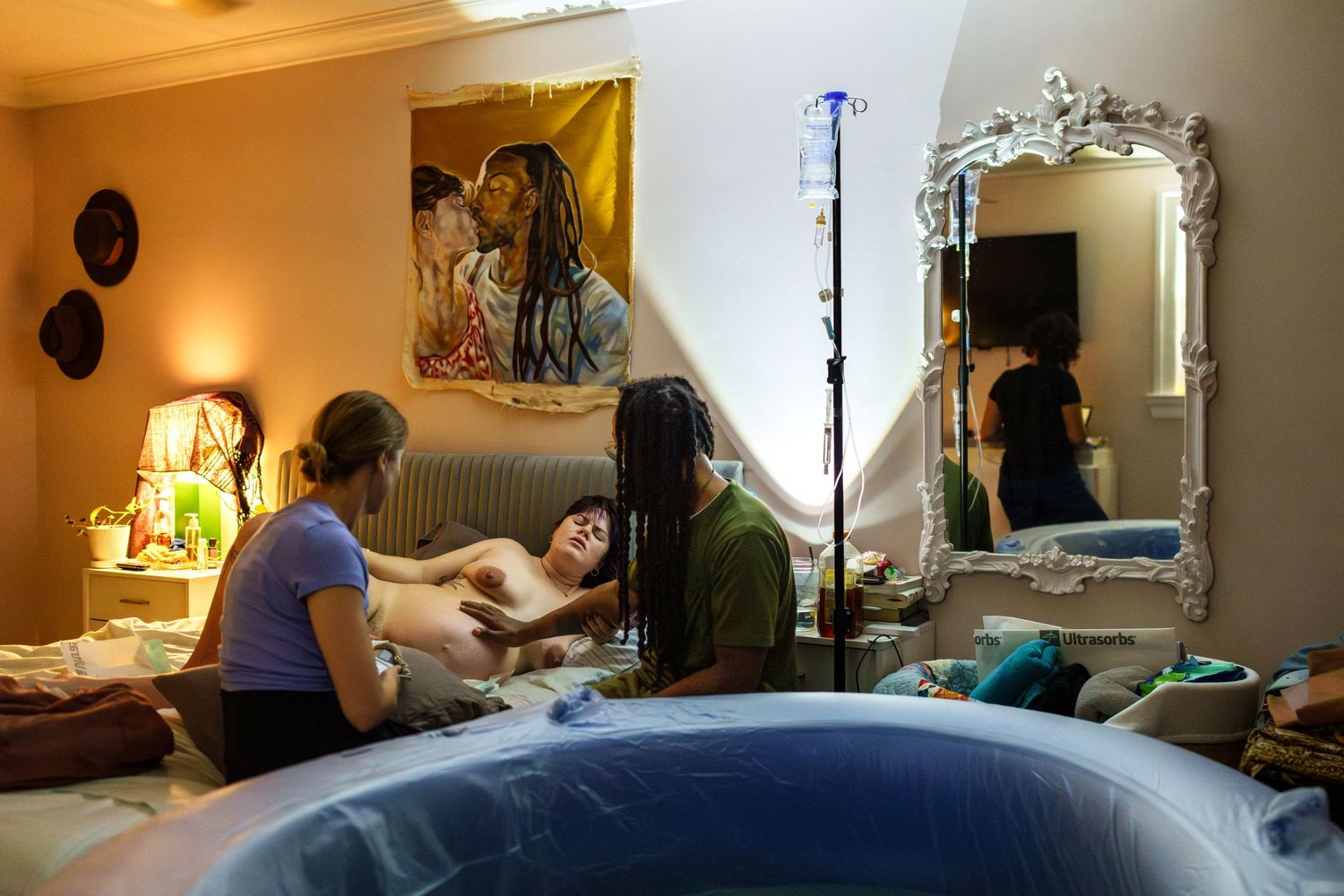 A Covington home birth midwife and the birthing persons partner comfort mom as she labors on a bed in her home in New Orleans.