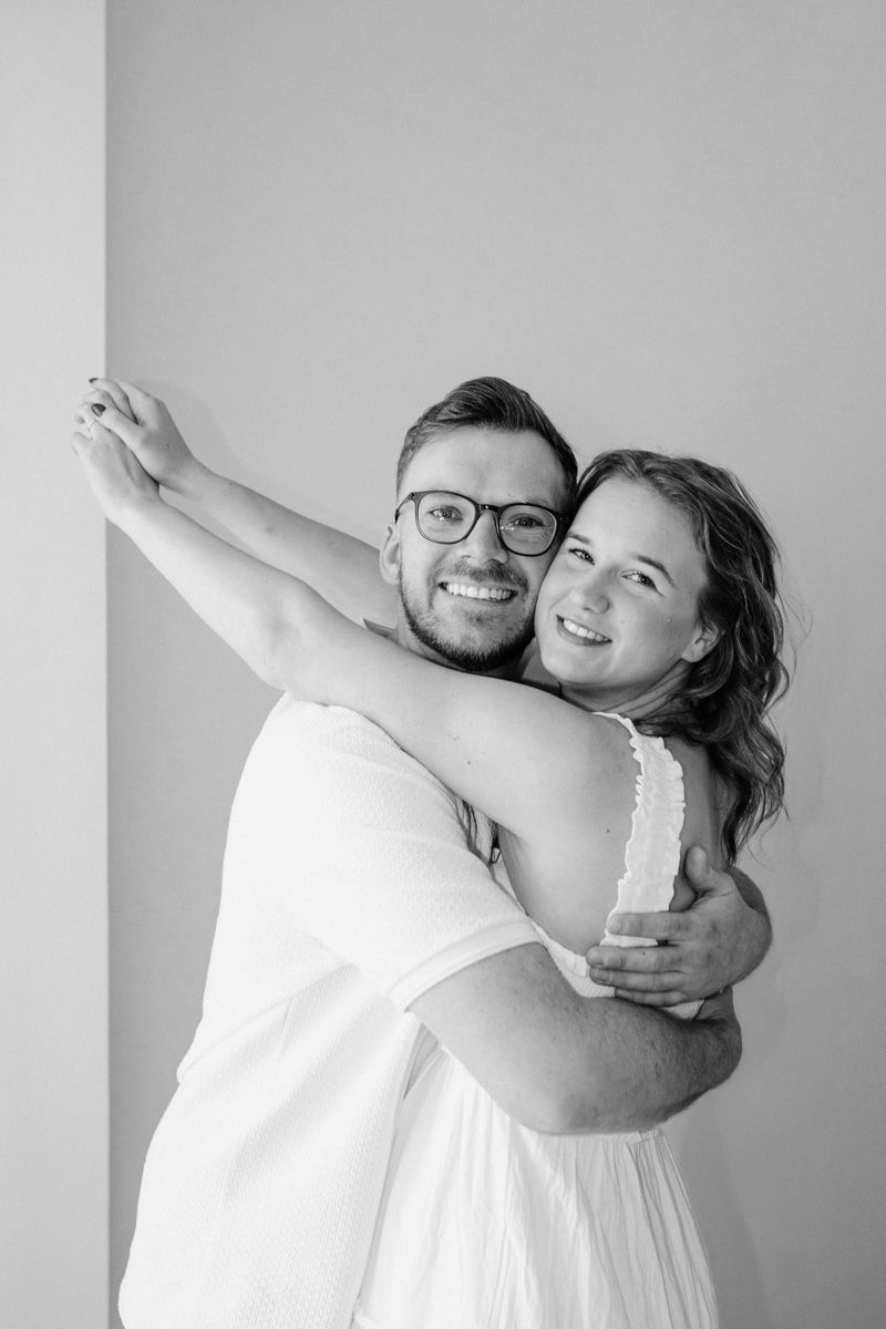 A couple in white clothing dances joyfully together in a minimalist black and white photo series.