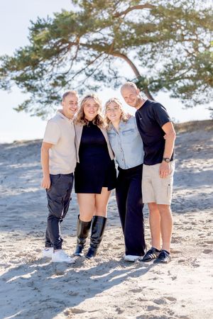 2 zussen samen met hun partners tijdens een familiefotoshoot. staan op de sahara. kijkend in de lens