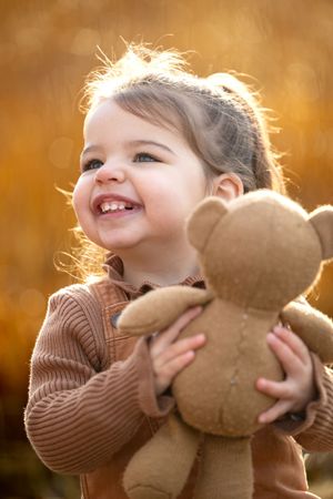 Meisje in bruine kleding met een teddybeer in haar handen