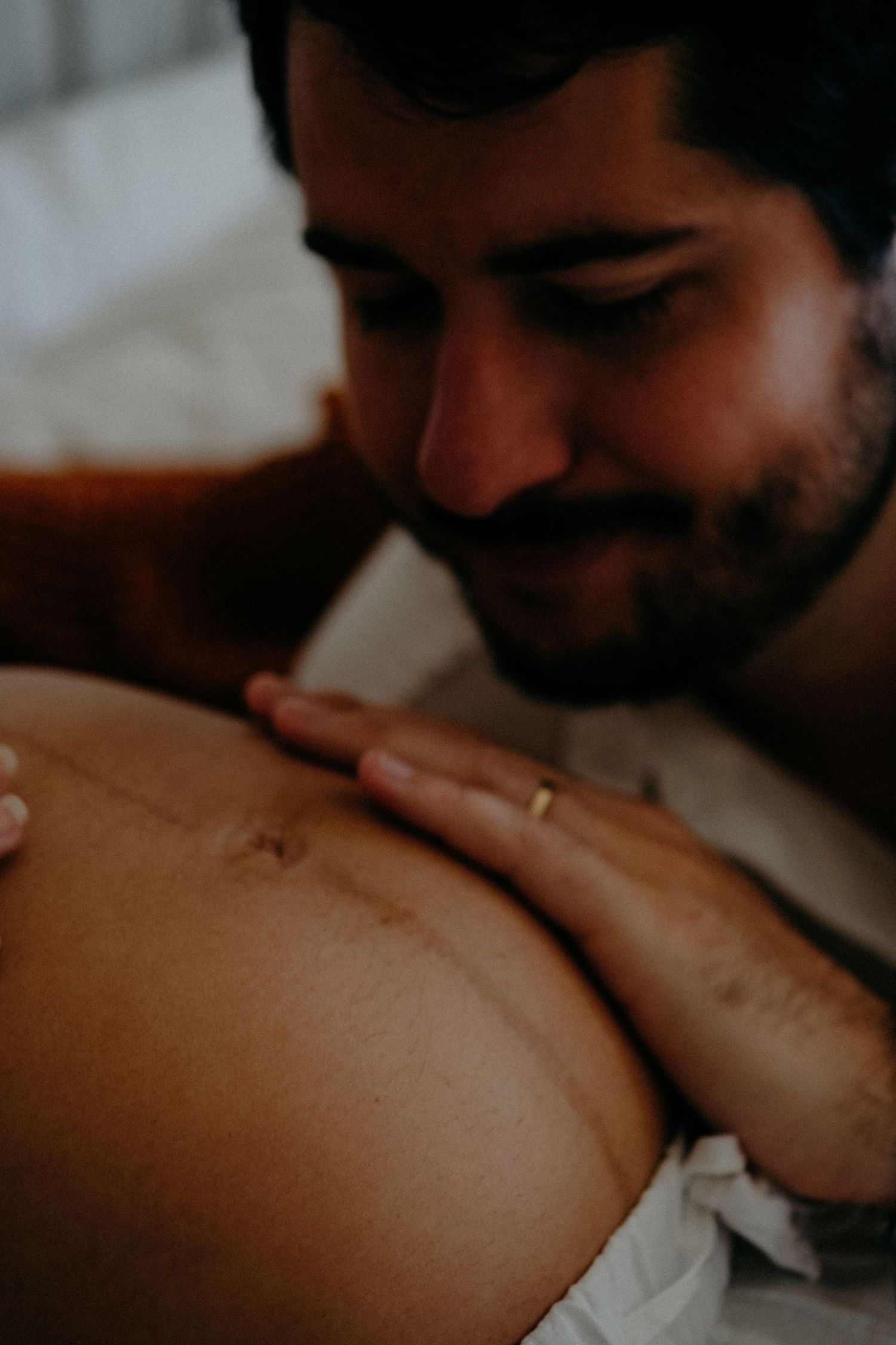 Partner gently kissing a pregnant belly during an intimate maternity photography session celebrating connection and anticipation.
