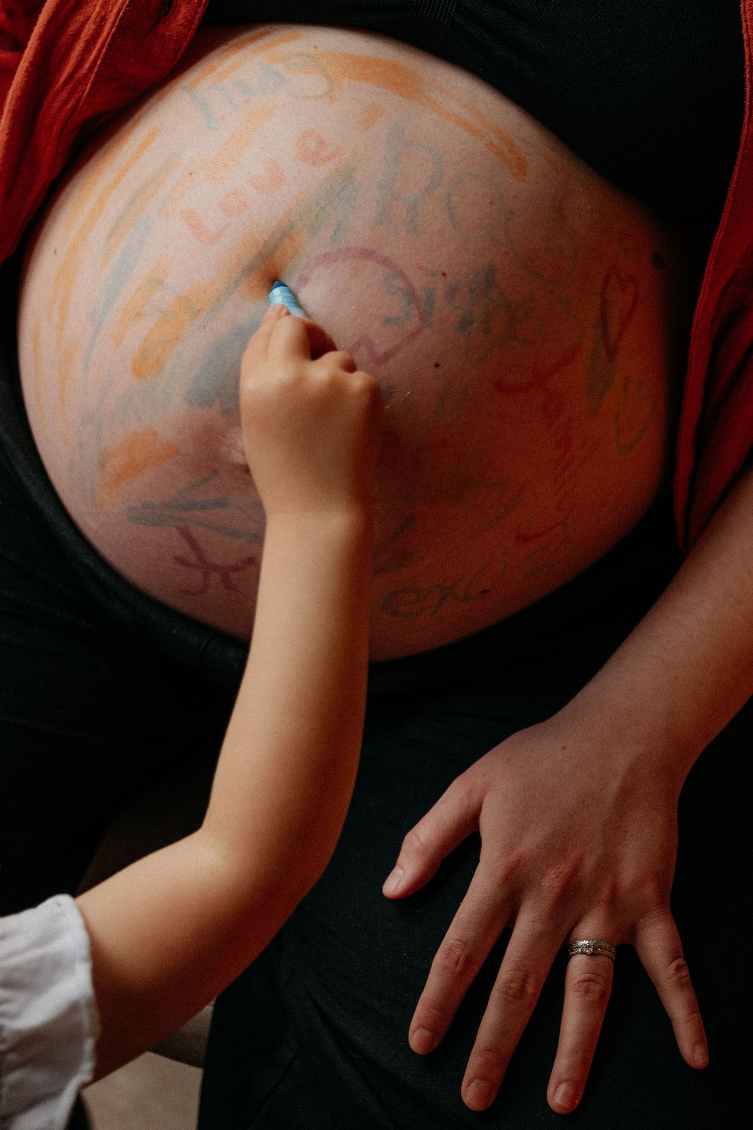 Child drawing something on mothers pregnant belly