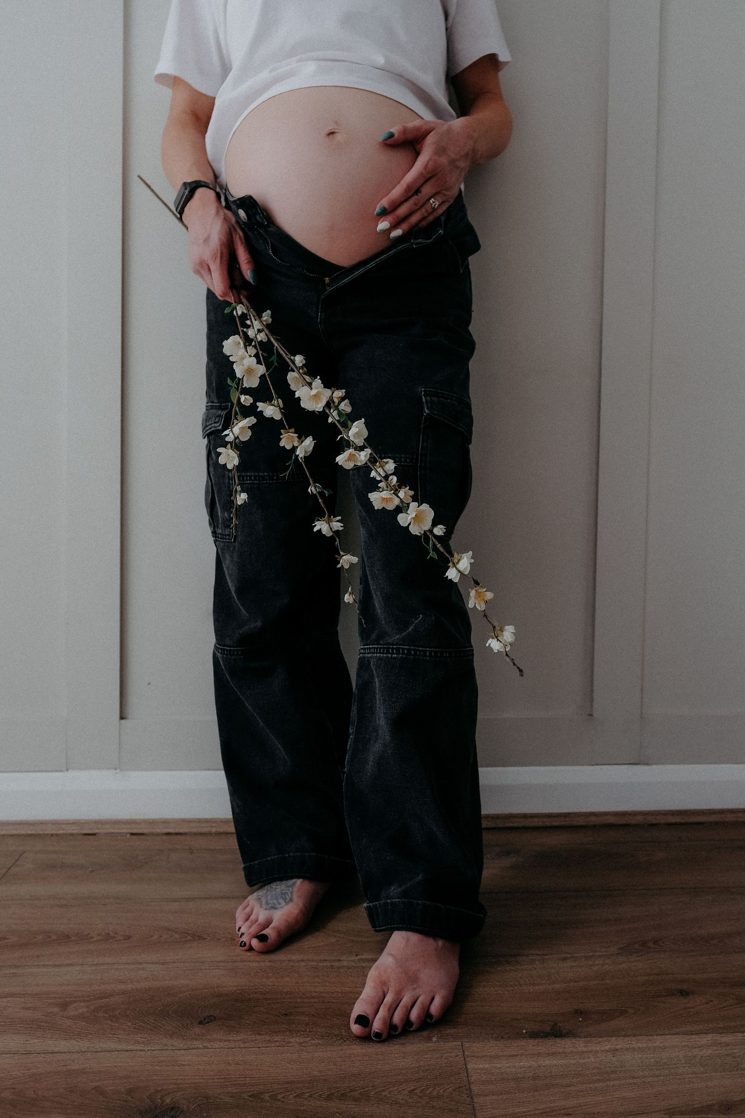 Pregnant mother standing indoors holding her bump during a relaxed maternity photography session in Northumberland.