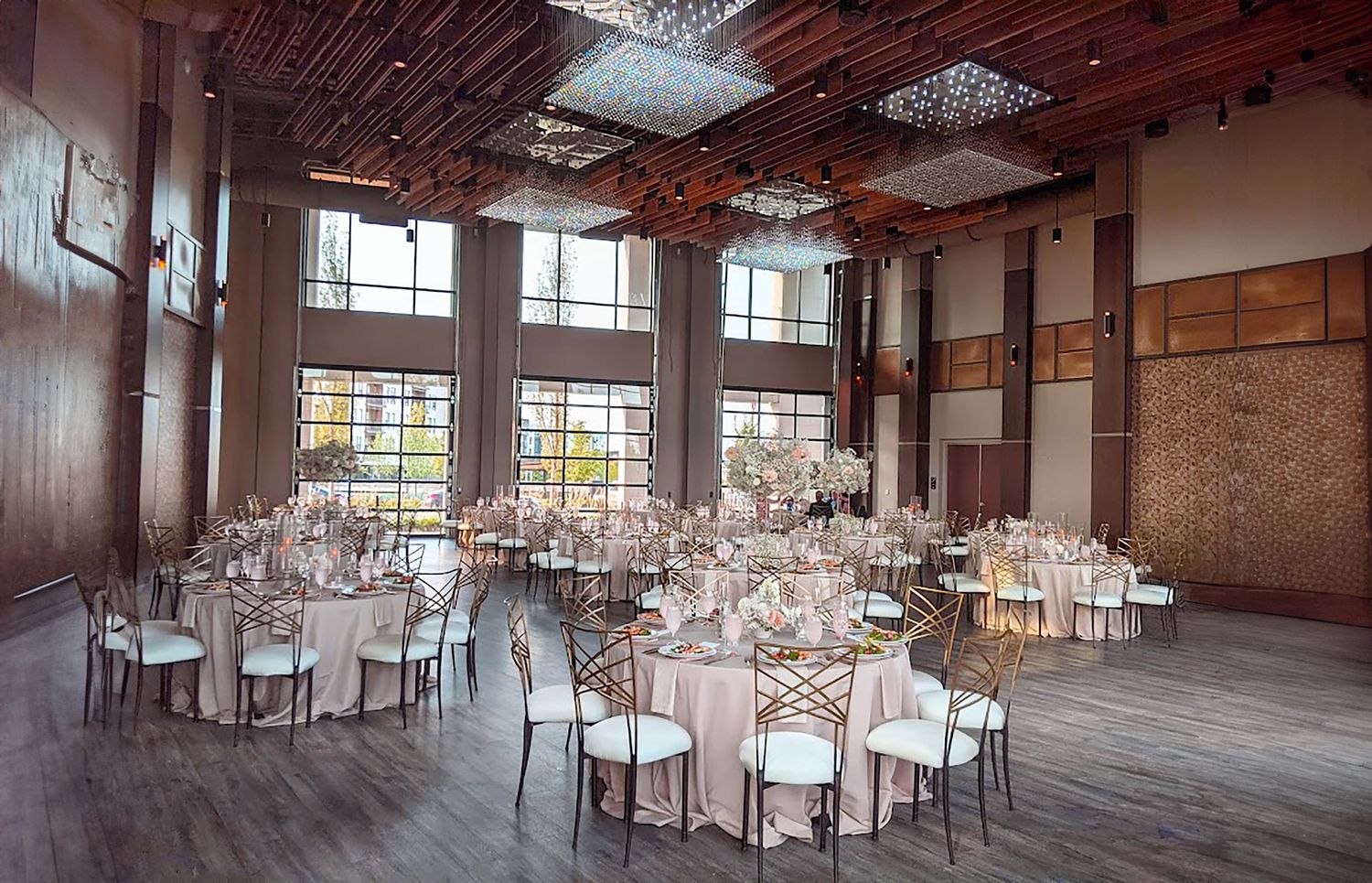 Spacious industrial-style venue with exposed beams and elegant table settings for wedding reception.