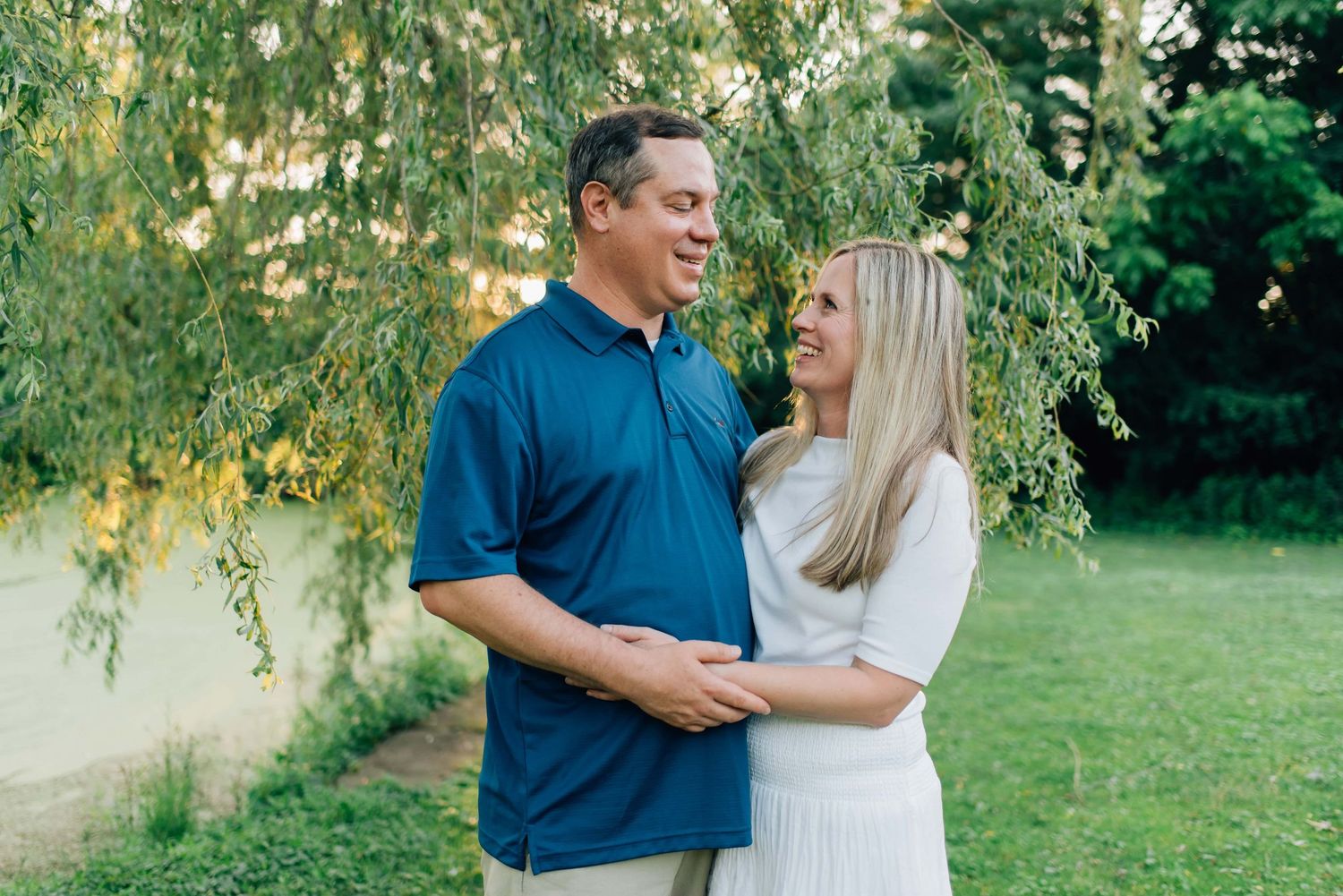 Parents smiling at each other under a willow tree at Succop Nature Park in Butler, PA