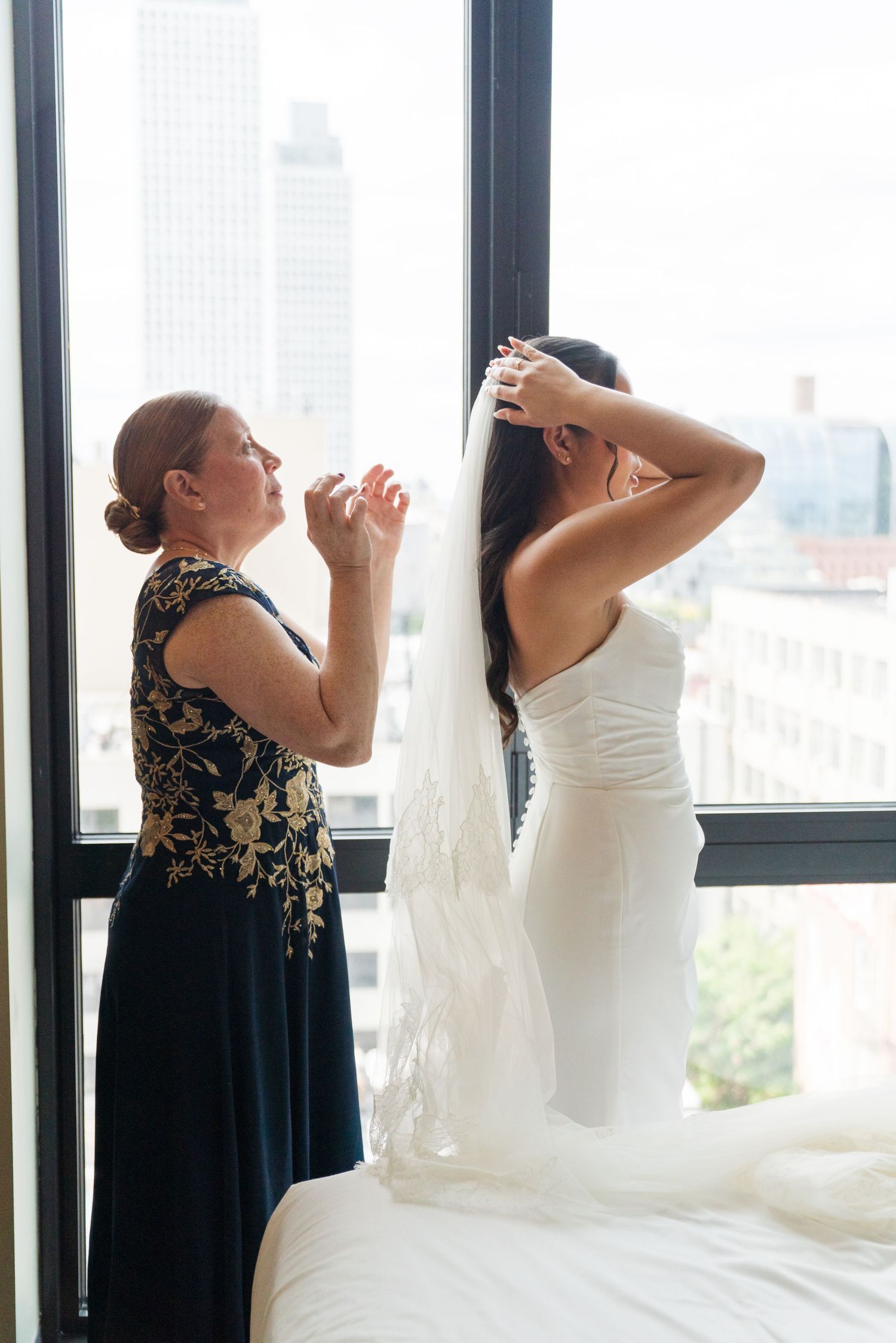 Wedding preparations by a window with city skyline views.
