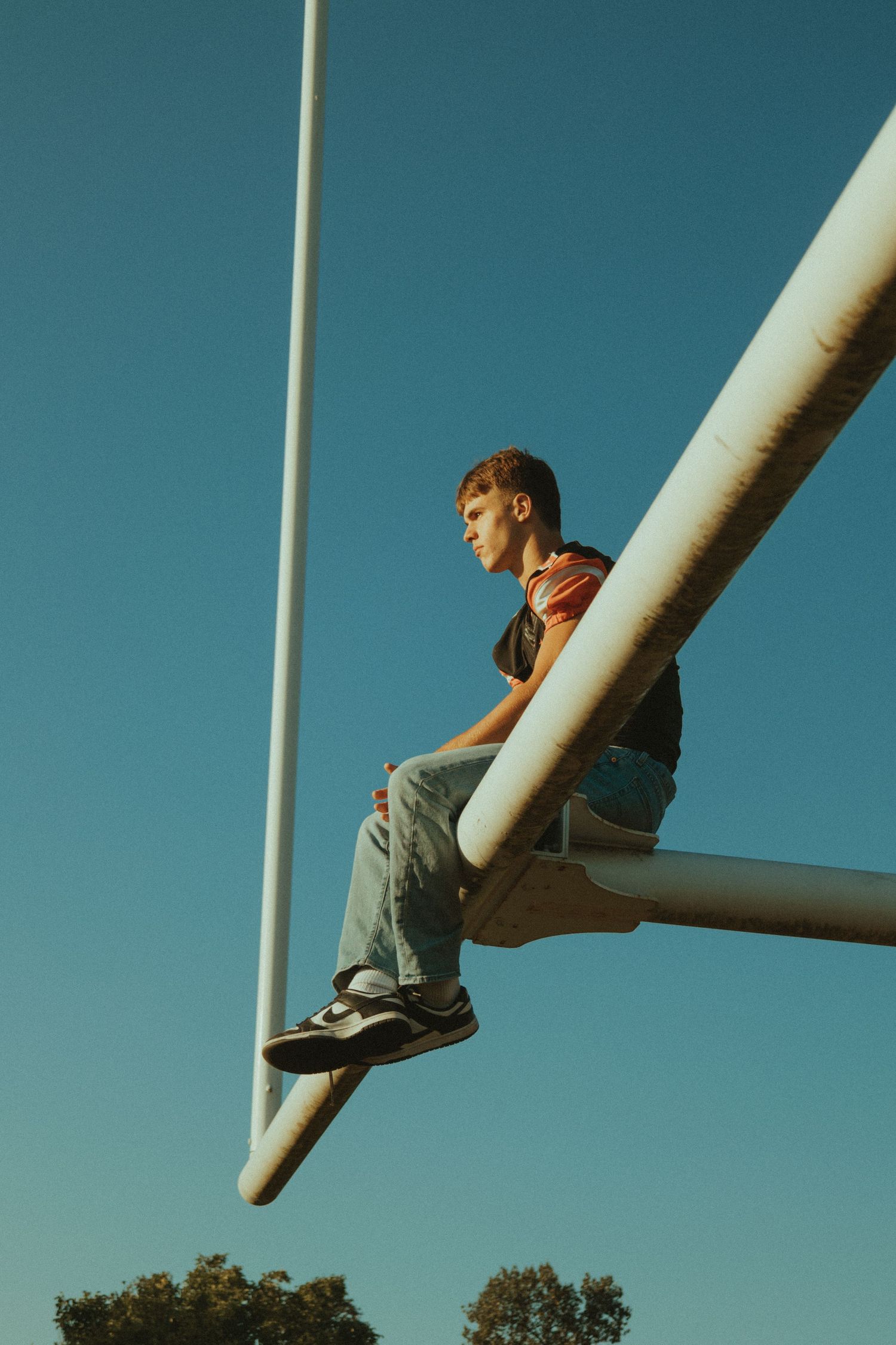 Creative perspective shot of sneakers against a blue sky with white pole creating diagonal composition.