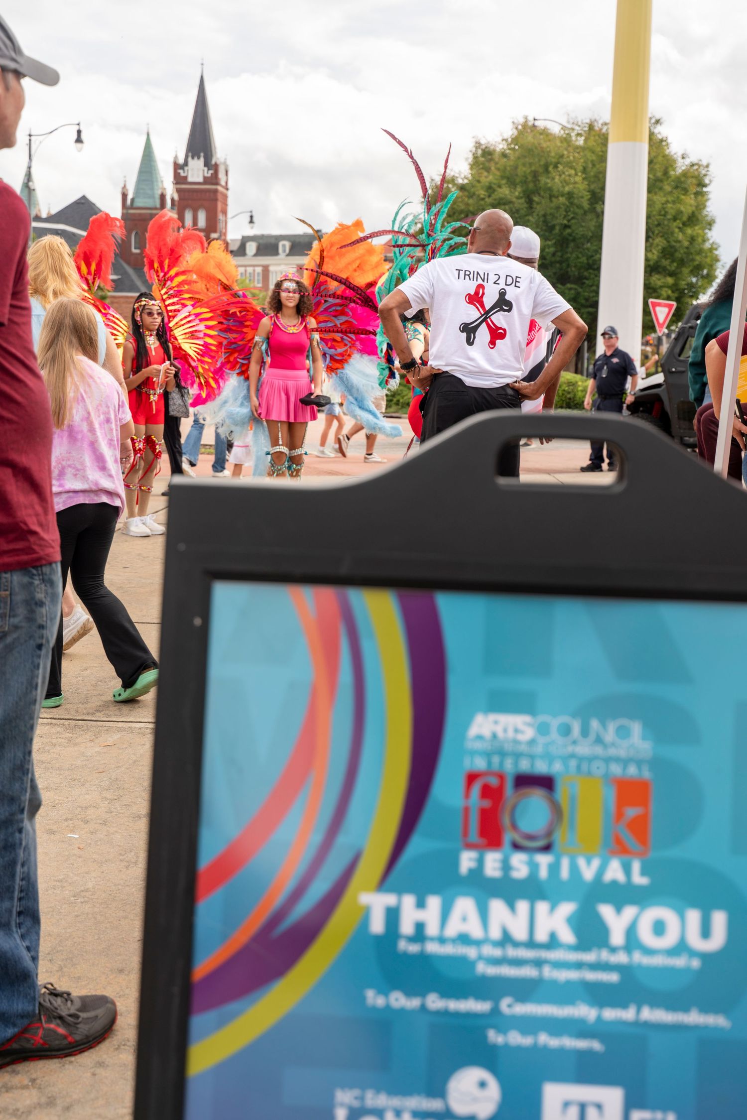 Colorful festival banners and signage with curved rainbow designs displayed at an outdoor community arts event.