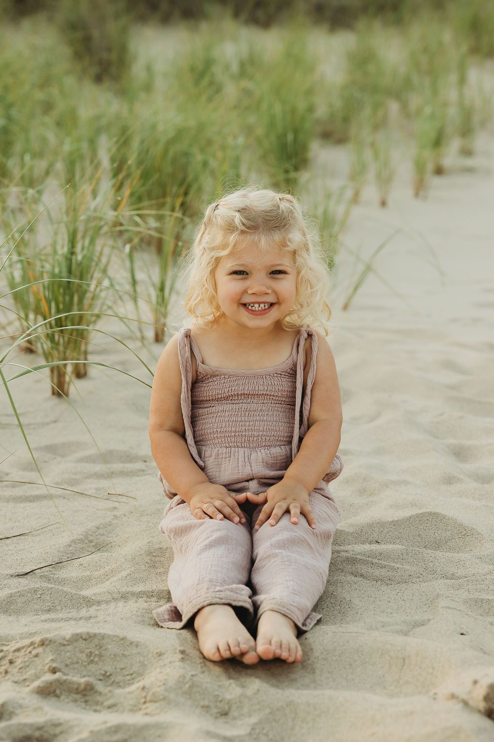 A series of photos showing a young child sitting and playing in beach sand dunes with tall grass in the background.