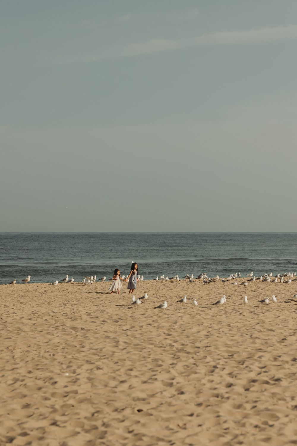 A serene beach landscape with beachgoers relaxing on sandy shores against a misty ocean horizon.