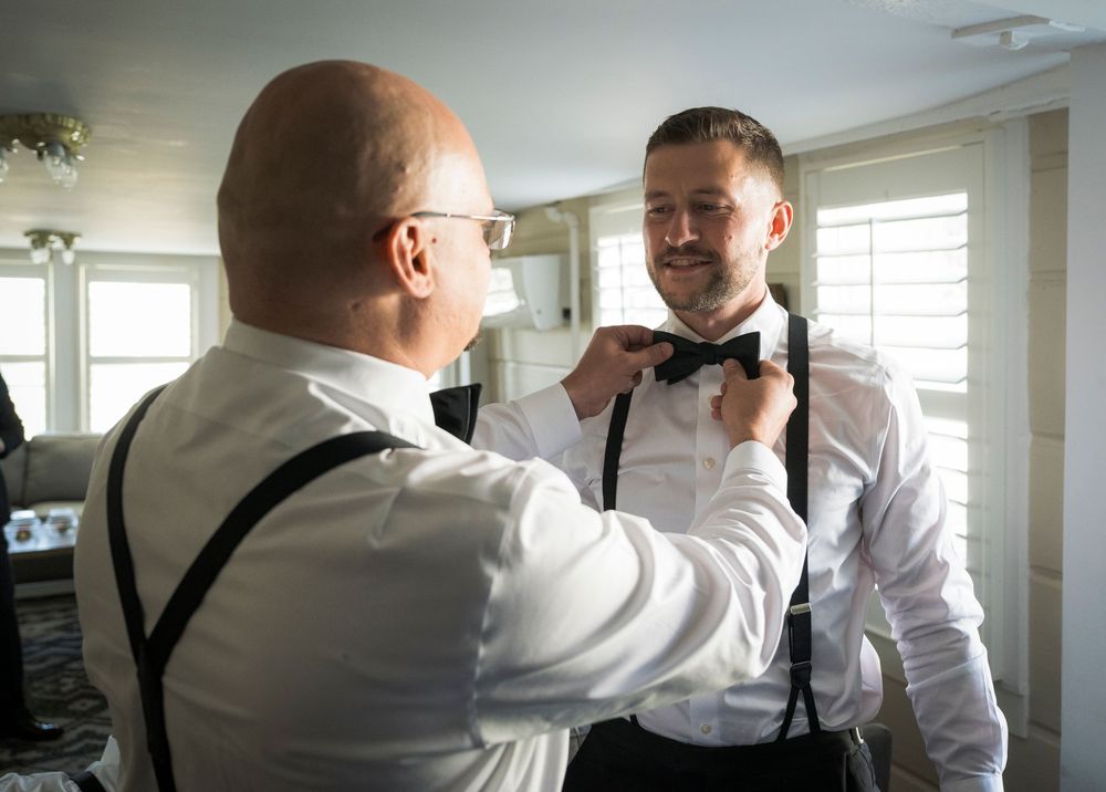 A series of photos showing someone adjusting a black bowtie on another person wearing a white dress shirt.