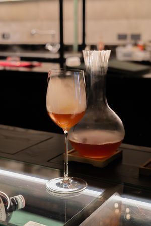 Amber-colored cocktails and glass decanters displayed on a dark bar counter.