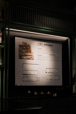 Illuminated architectural floor plans displayed on dark walls in an exhibition space.
