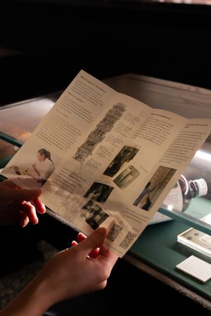 Hands flipping through pages of a vintage photo album or document with black and white photographs.