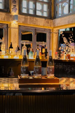 Illuminated bar display with vintage bottles and glassware in warm lighting.