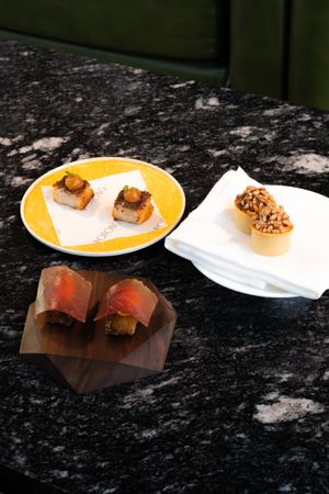 Artfully plated sushi with garnishes served on white plates against a dark textured background.