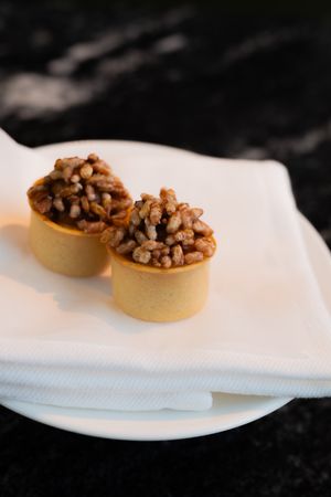 Small appetizers with chopped nuts served on white plates.