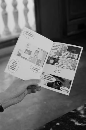 A series of black and white comic strip panels being held up and displayed in sequence.