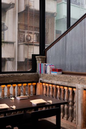 Long wooden table with balustrade railing in an industrial-style dining space.