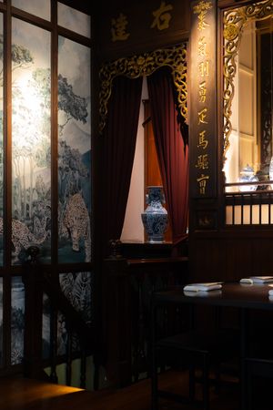 Elegant restaurant interior with ornate wall decorations and dark wood paneling illuminated by warm lighting.