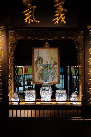 Traditional Asian decor display with porcelain vases and artwork in dim lighting.