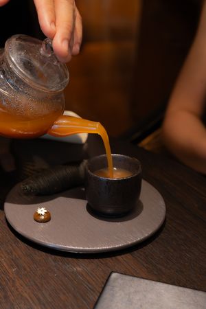 Amber liquid being poured onto a dark circular plate in a dimly lit setting.