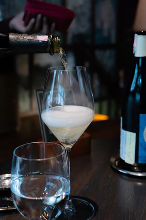 Wine glasses filled with frothy white cocktails on a dark wooden table.