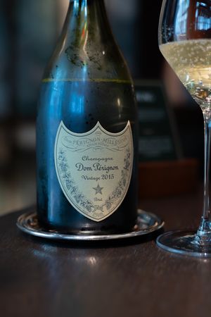 A bottle of Dom Perignon champagne displayed on a dark wooden surface with glasses.