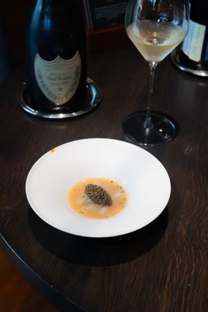 Elegant plated dish with caviar and sauce served alongside wine glass.