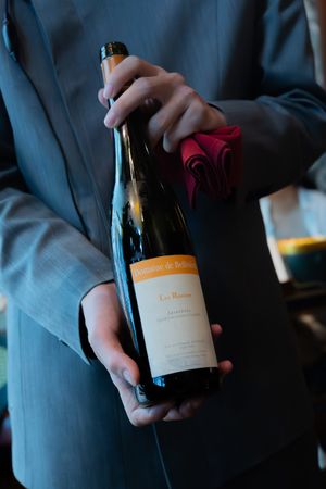 Wine bottle being presented in dimly lit restaurant setting.
