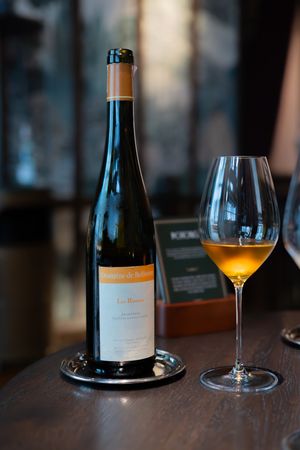 Wine bottles and glasses arranged on a dark wooden table with golden liquid catching the light.