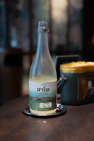 Glass bottles of specialty beverages arranged on a dark wooden restaurant table.