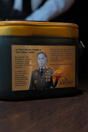 Decorative tin container with military-themed artwork and text on a dark wooden surface.